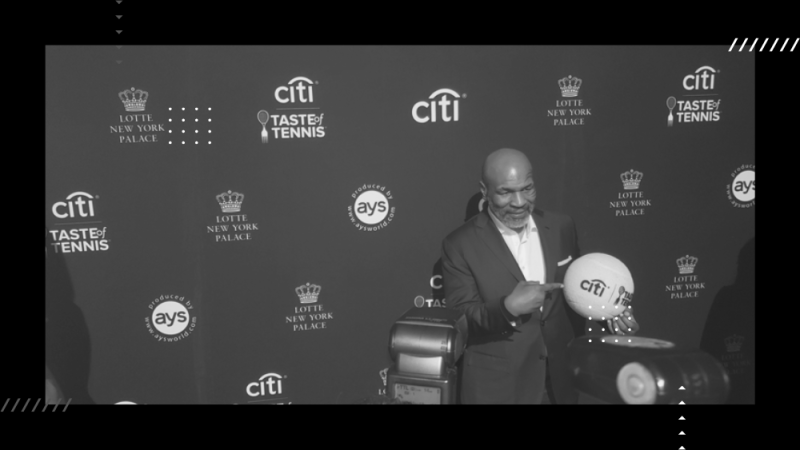 How Does an Athlete’s Presence Enhance the event - Eli Lunzer Productions Blog Featured Image Mike Tyson at event holding a branded product with his photo being taken.